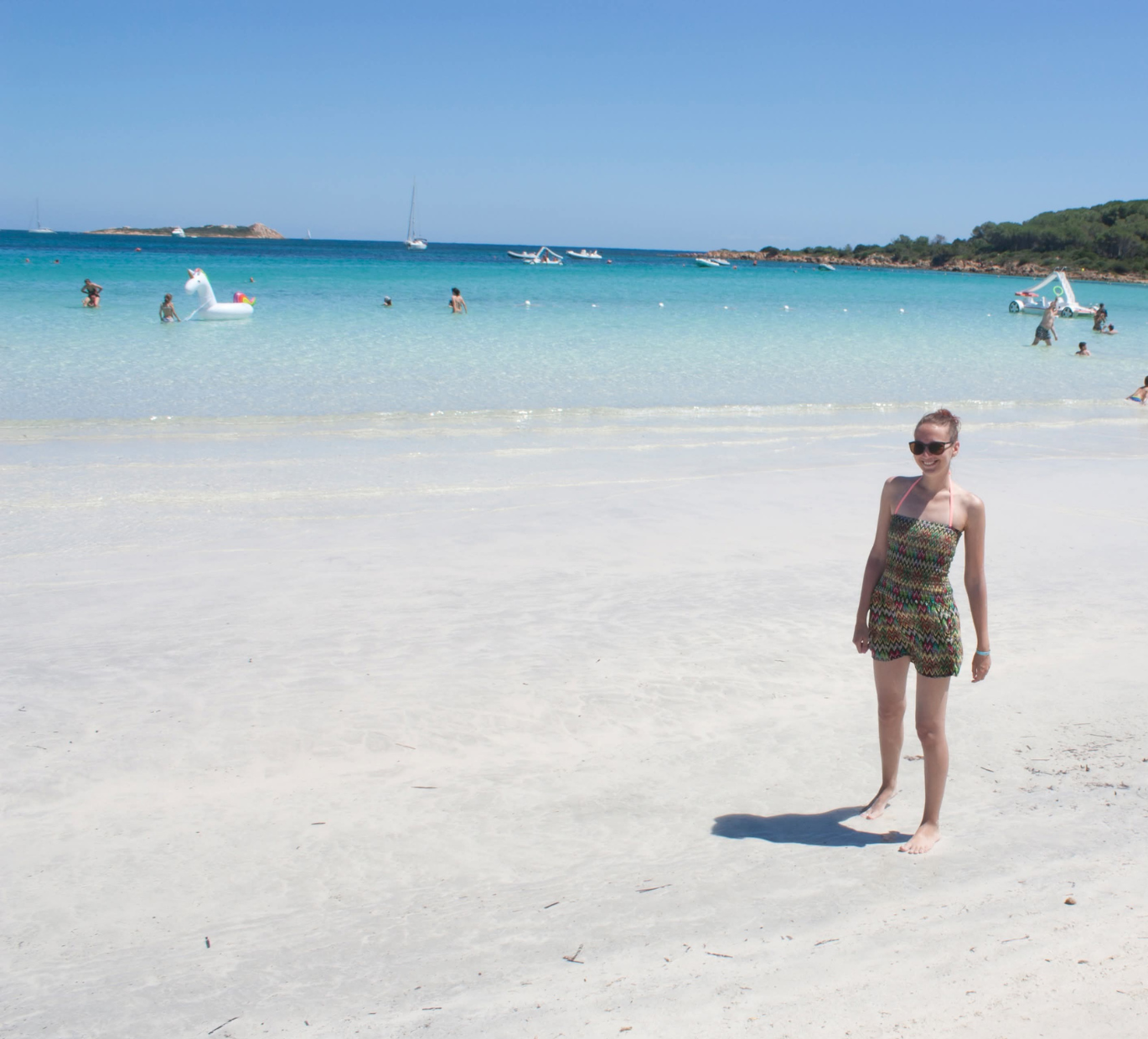 Autorin Jo Jonson steht auf einem großen weißen Sandstrand und hinter ihr das türkisblaue Meer beim Urlaub auf Sardinien