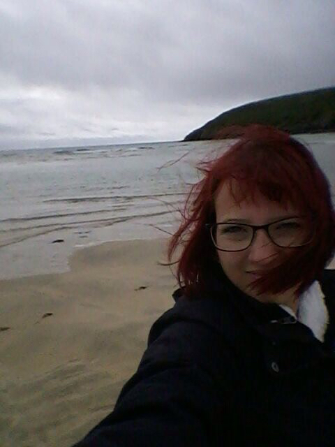 Jessica Jirschik in Irland im Herbst am Strand während der Wind ihr das rote Haar ins Gesicht weht