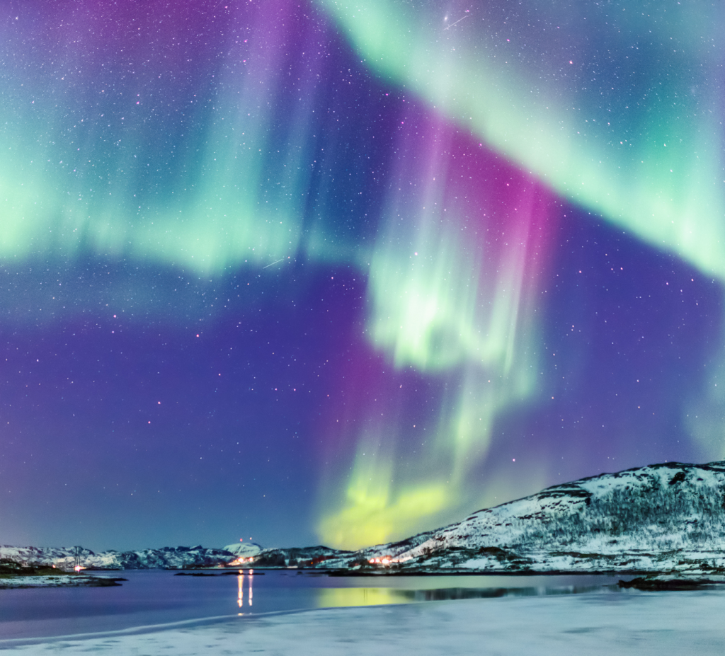 lila Himmel, über dem die Nordlichter über einer verschneiden Landschaft leuchten. Das Bild fängt die Stimmung von meinem Winter-Liebesroman in Finnland perfekt ein